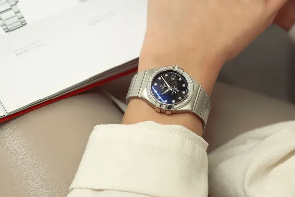 an image of a female model waring a steel color watch with a black dial and diamond hour markers